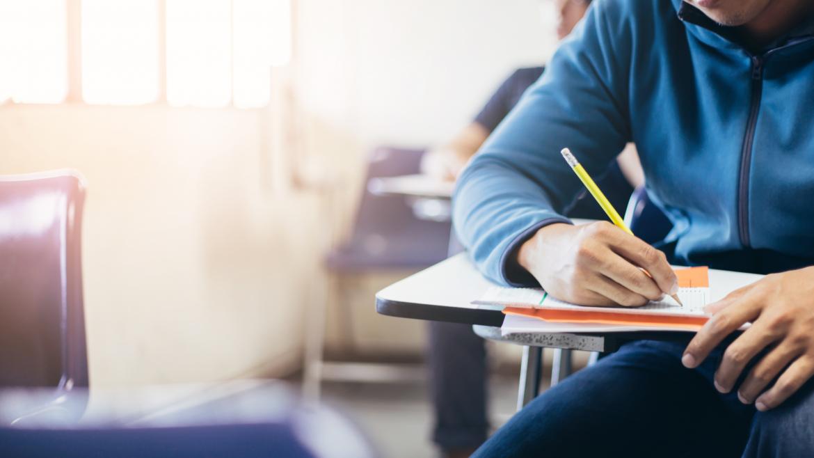 Un estudiante universitario escribiendo con un lápiz