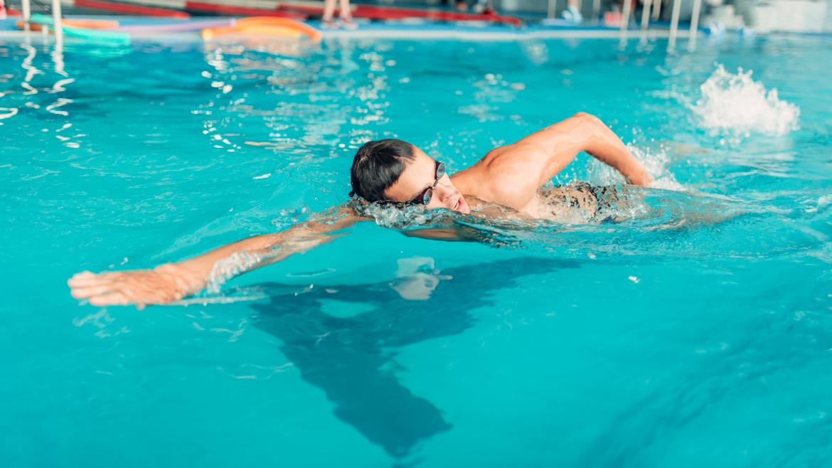 Hombre con gafas realizando natación en piscina cubierta